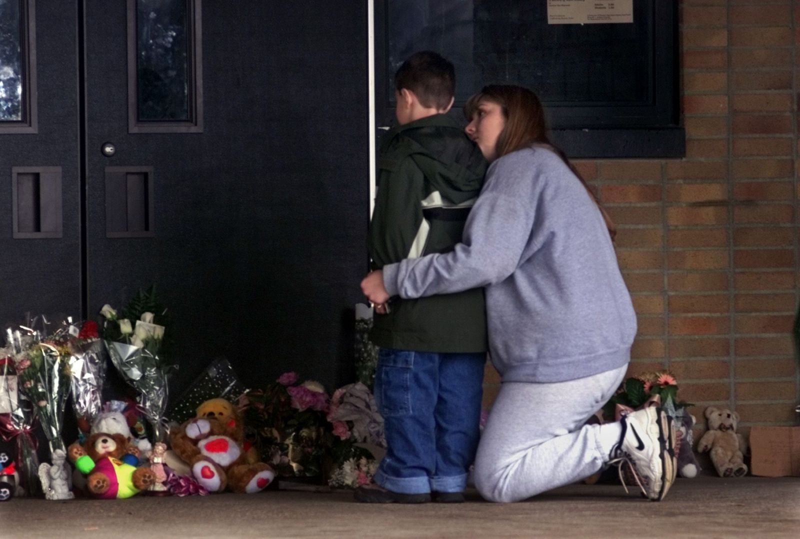 Žiak s matkou pokladá kvety pred školu, v ktorej zomrela Kayla Rolland