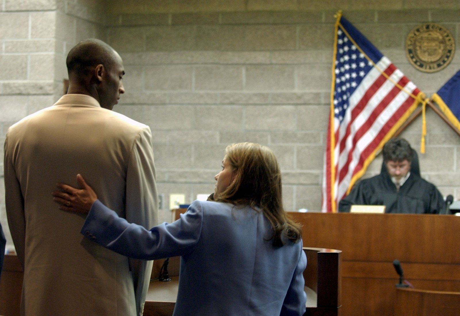 Kobe sa pozerá na svoju obhajkyňu Pamelu Mackeyovú, kým ho sudca Frederick Gannet poúča o jeho právach, počas súdneho pojednávania v coloradskom meste Eagle 6. augusta