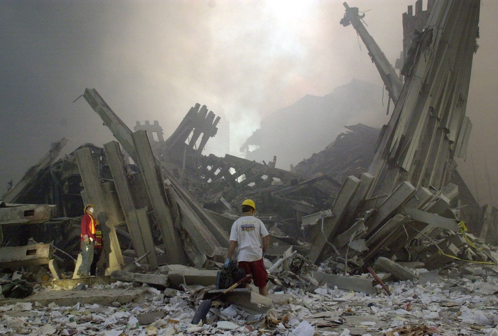 Členovia záchranárskych skupín stoja uprostred ruín dvoch budov Svetového obchodného centra (WTC) 11. septembra v New Yorku.